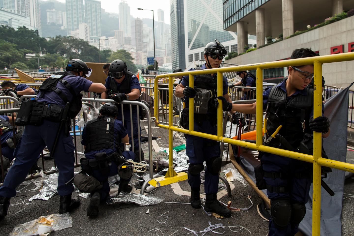 Police officers remove barricades at an area previously blocked by pro-democracy supporters near the government headquarters building at the financial Central district in Hong Kong