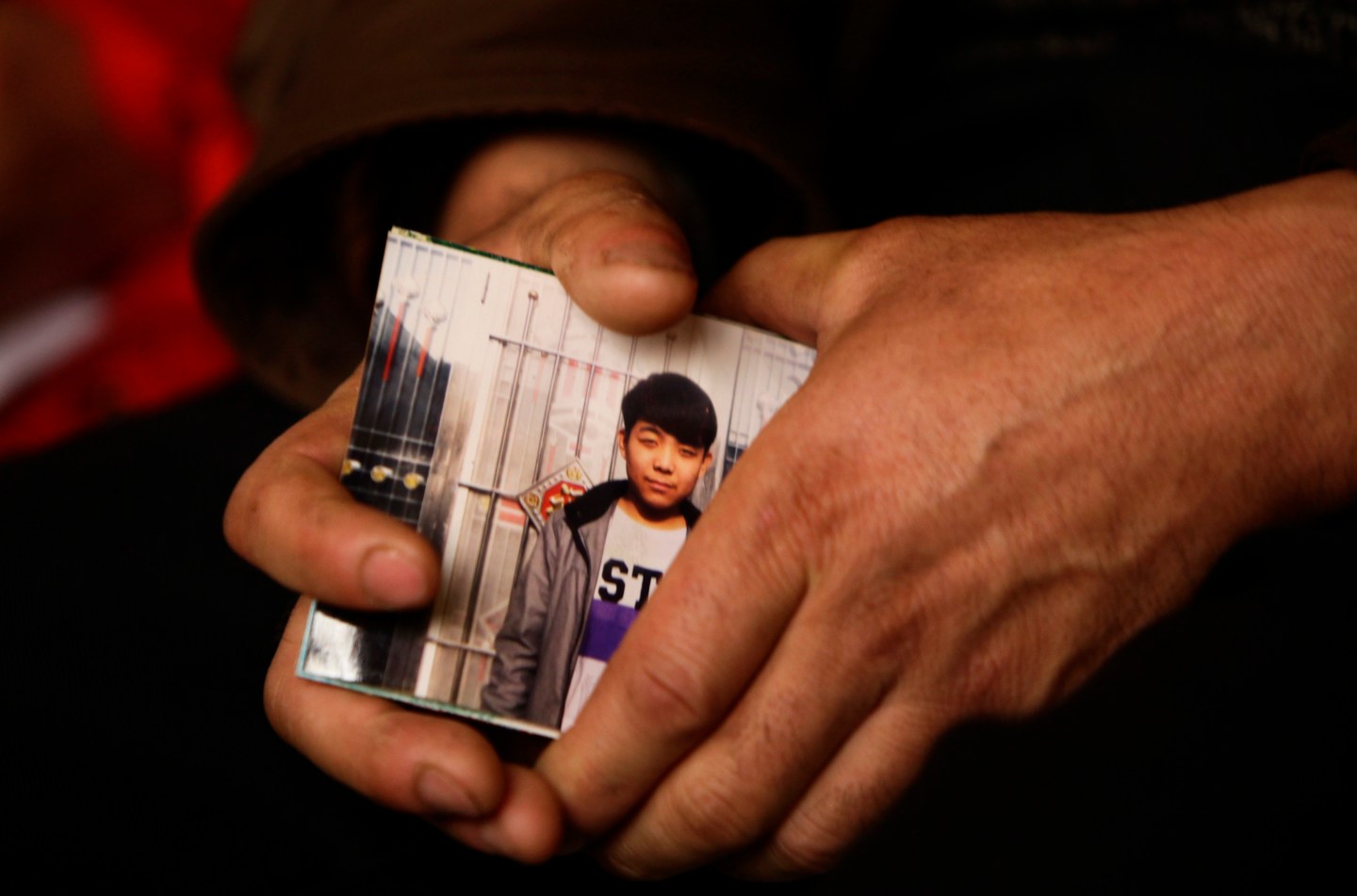 The father of the 15-year-old Pegatron worker who died of pneumonia, holds his son's picture at a news conference in Beijing