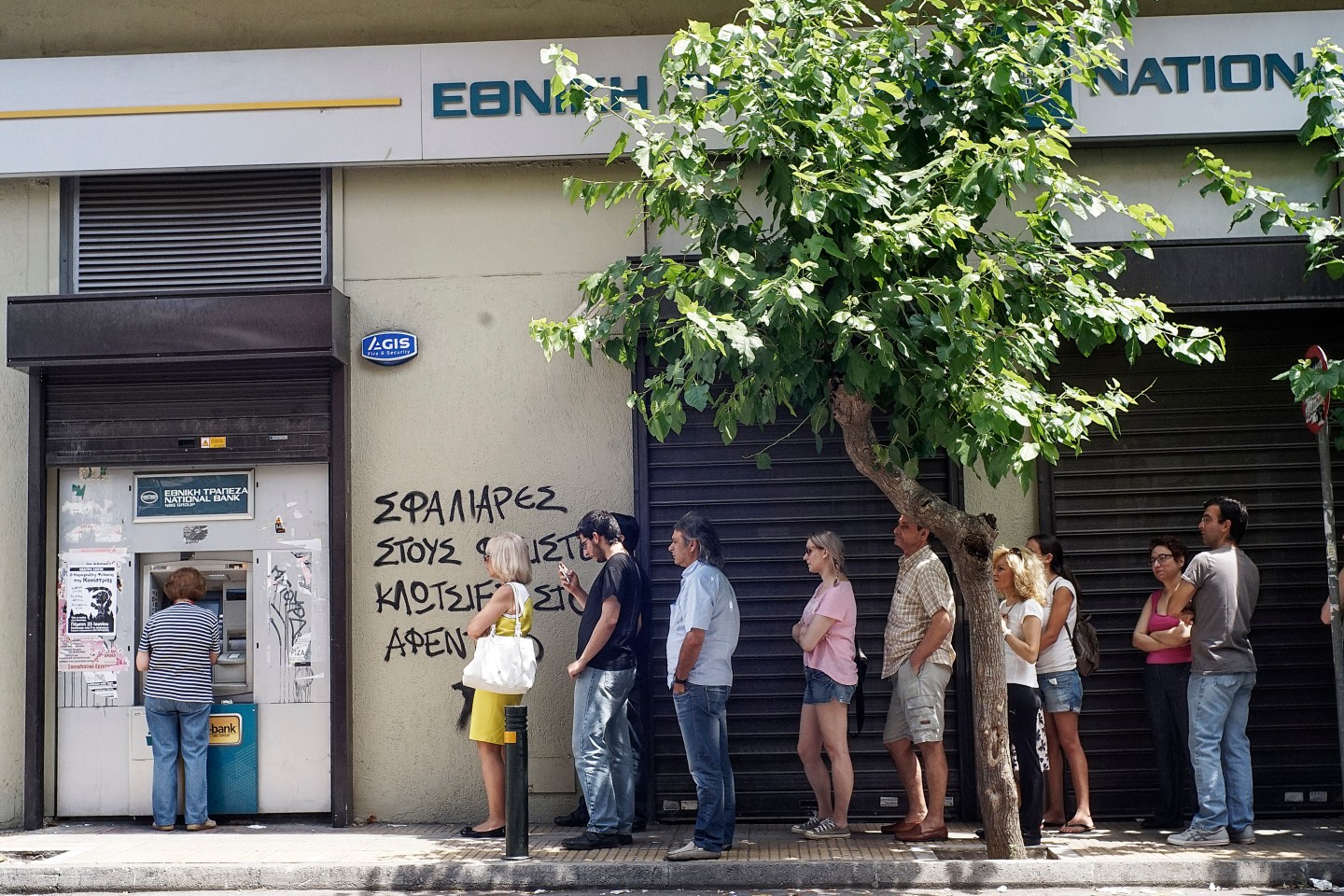 Greeks queue in front of the National Bank to use ATM to withdraw cash as Parliament holds an emergency session for the government's proposed referendum June 27, 2015 in Athens, Greece.