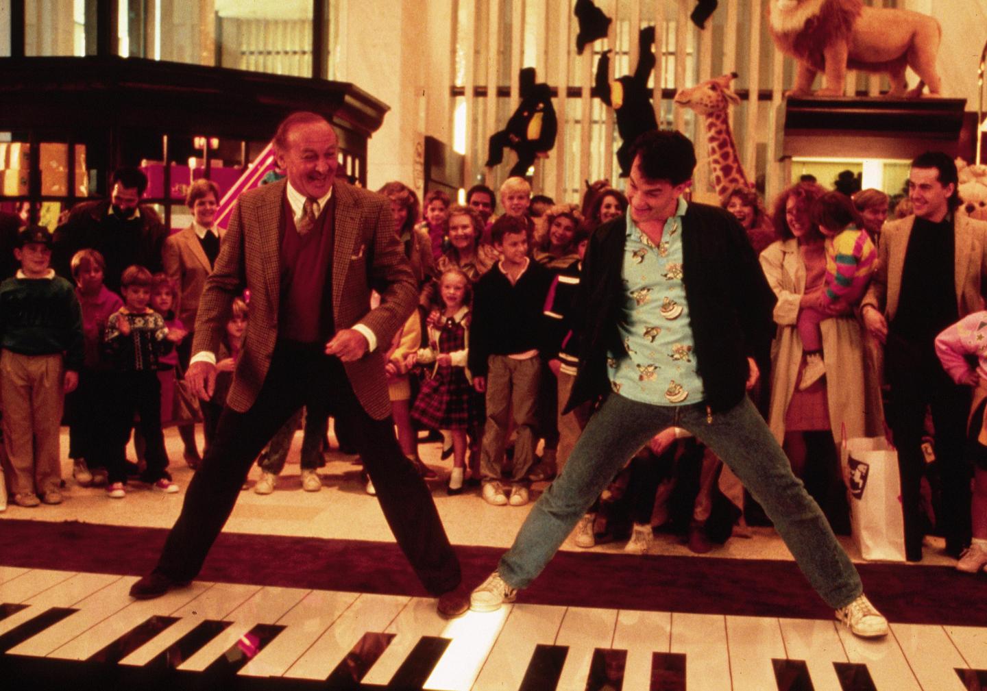 Caption:1988, American actors Robert Loggia, left, and Tom Hanks stand on a giant piano keyboard at the FAO Schwartz toy store in a still from the film 'Big' directed by Penny Marshall.