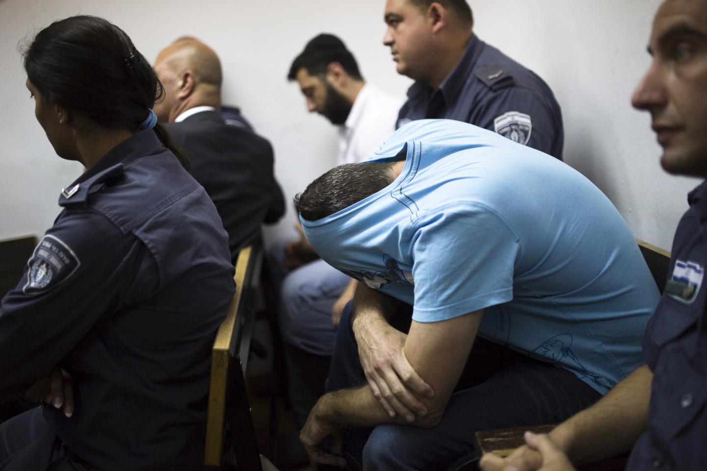 Orenstein, who is accused by U.S. authorities of engaging in a stock manipulation scheme involving U.S. penny stocks, hides his face in his T-shirt as he sits in a courtroom at the Jerusalem Magistrates Court