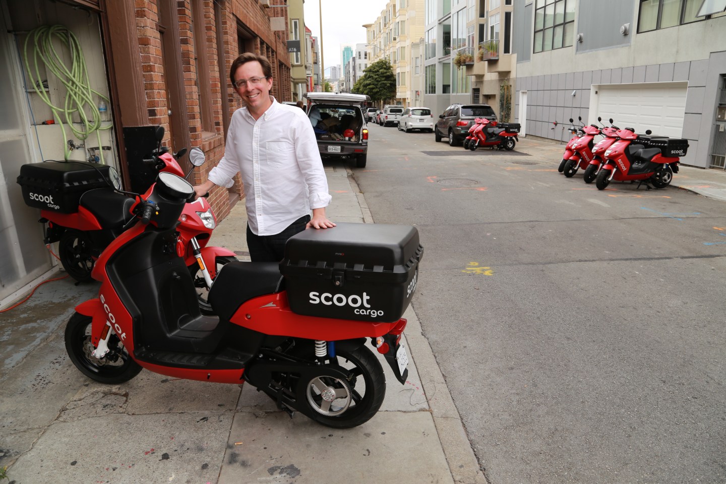 Scoot Networks CEO Michael Keating stands behind the company's new cargo scooters in front of HQ.