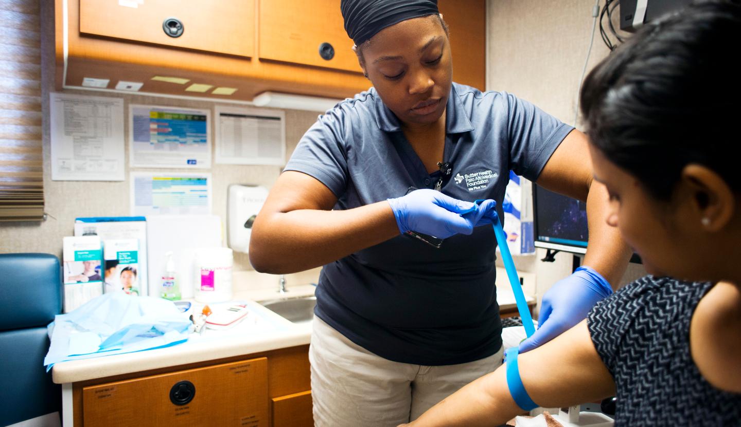 Milpitas, California - October 1:Gena Rayford draws and examines blood samples from Teja Krishna Bagenalli, a patient aboard Sutter Health's "Care-A-Van" which travels to a variety of sillicon valley companies, providing on site exams.