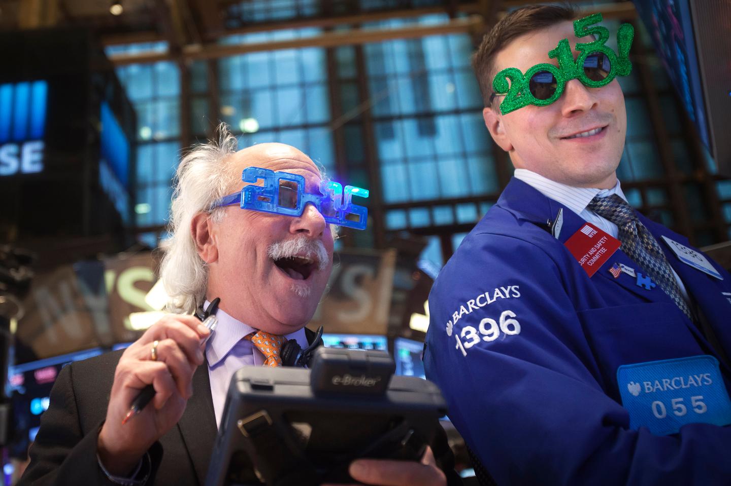 Traders Tuchman and Mastrolia work on the floor of the New York Stock Exchange while wearing 2015 novelty glasses on New Year's Eve, the last trading day of the year, in New York