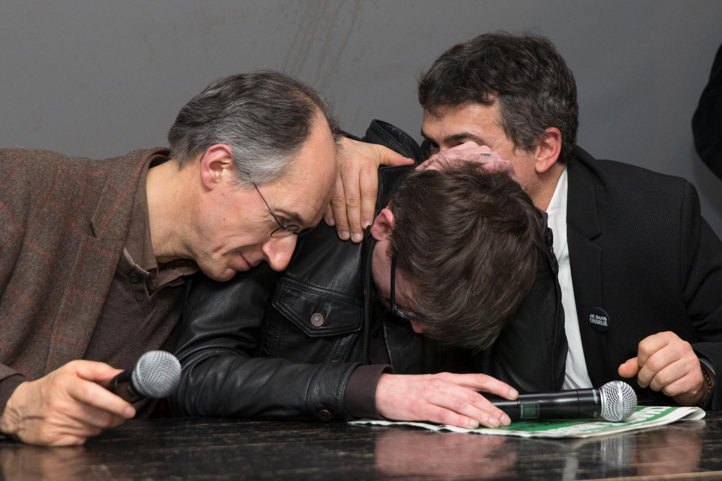 Satirical French magazine Charlie Hebdo new editor in chief Briard and columnist Pelloux comfort cartoonist Luz during a news conference at the French newspaper Liberation offices