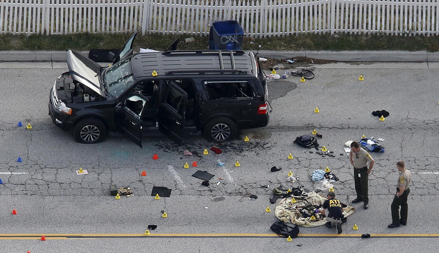 Law enforcement officers look over the evidence near the remains of a SUV involved in the Wednesdays attack is shown in San Bernardino, California