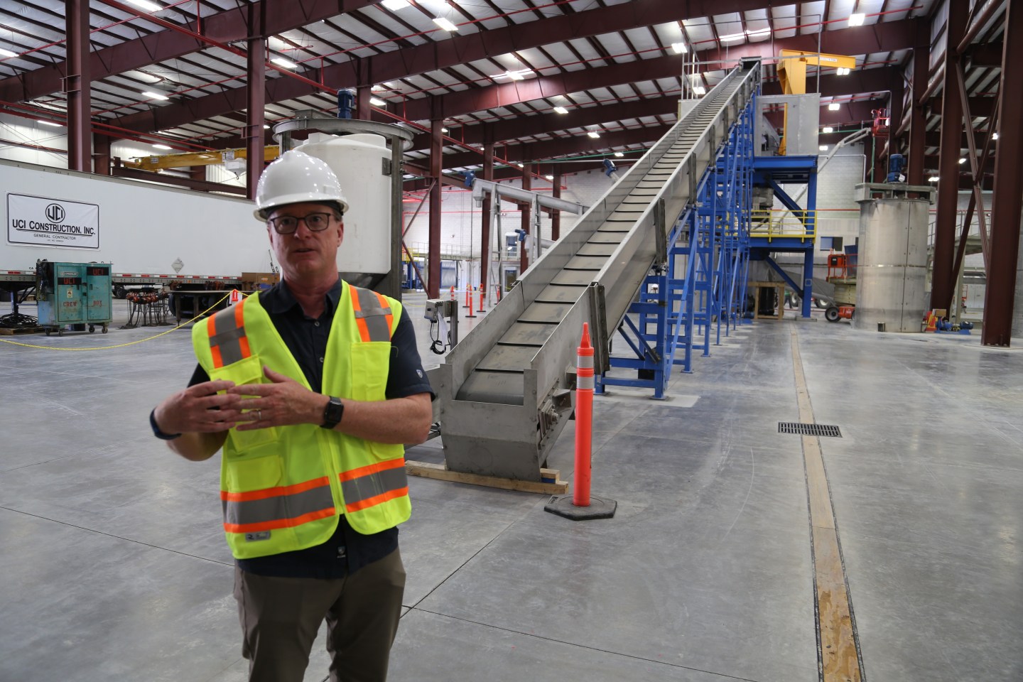 Aqua Metal's Chief Commercial Office Steve Cotton stands in front of the machine that tears the batteries apart.