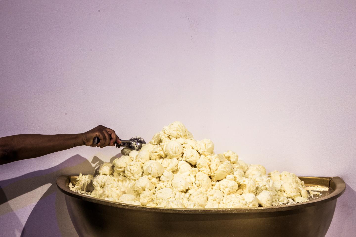 An attendee scoops vegetable shortening laced with sugar to deposit it into "The World's Largest Ice Cream Sundae" during a press preview of the Museum of Ice Cream in New York.