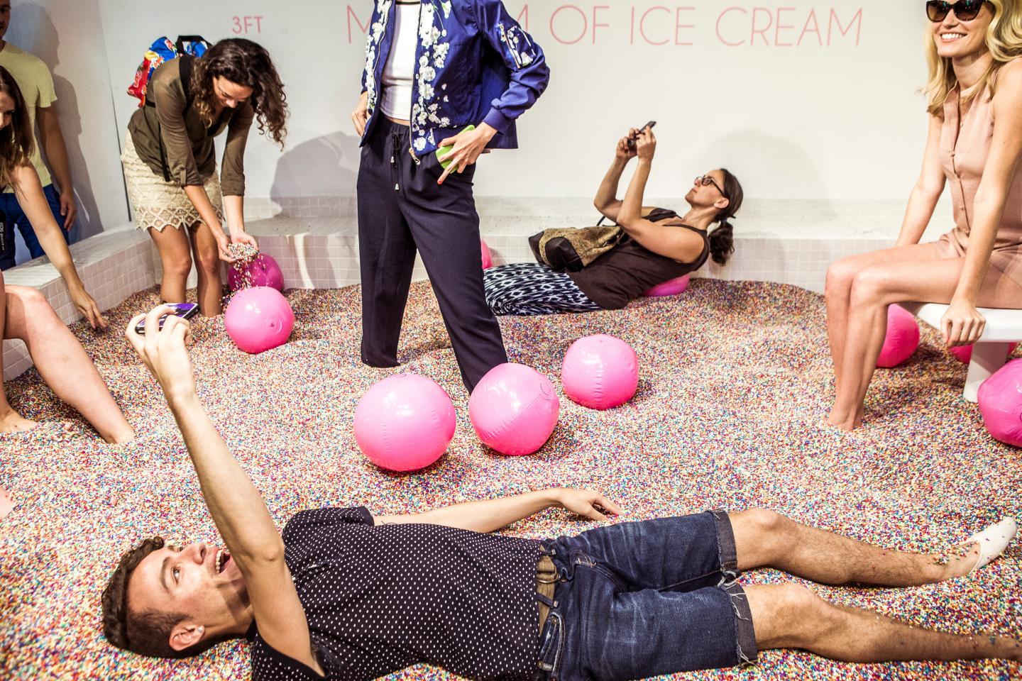 Attendees play and take photos in a pool of non-edible sprinkles during a press preview of the Museum of Ice Cream in New York.