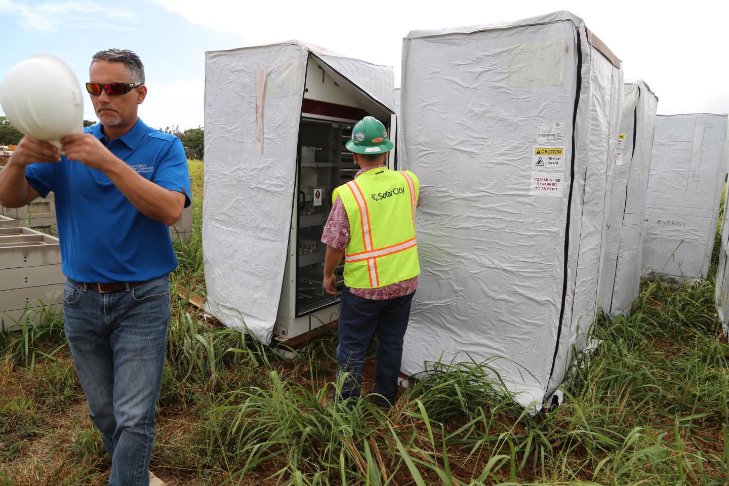 Kauai Island Utility Cooperative's Engineering Manager John Cox (L) and SolarCity's Senior Commercial Project Manager Danny Valdez (R) check out a Tesla inverter for a new solar and battery system.