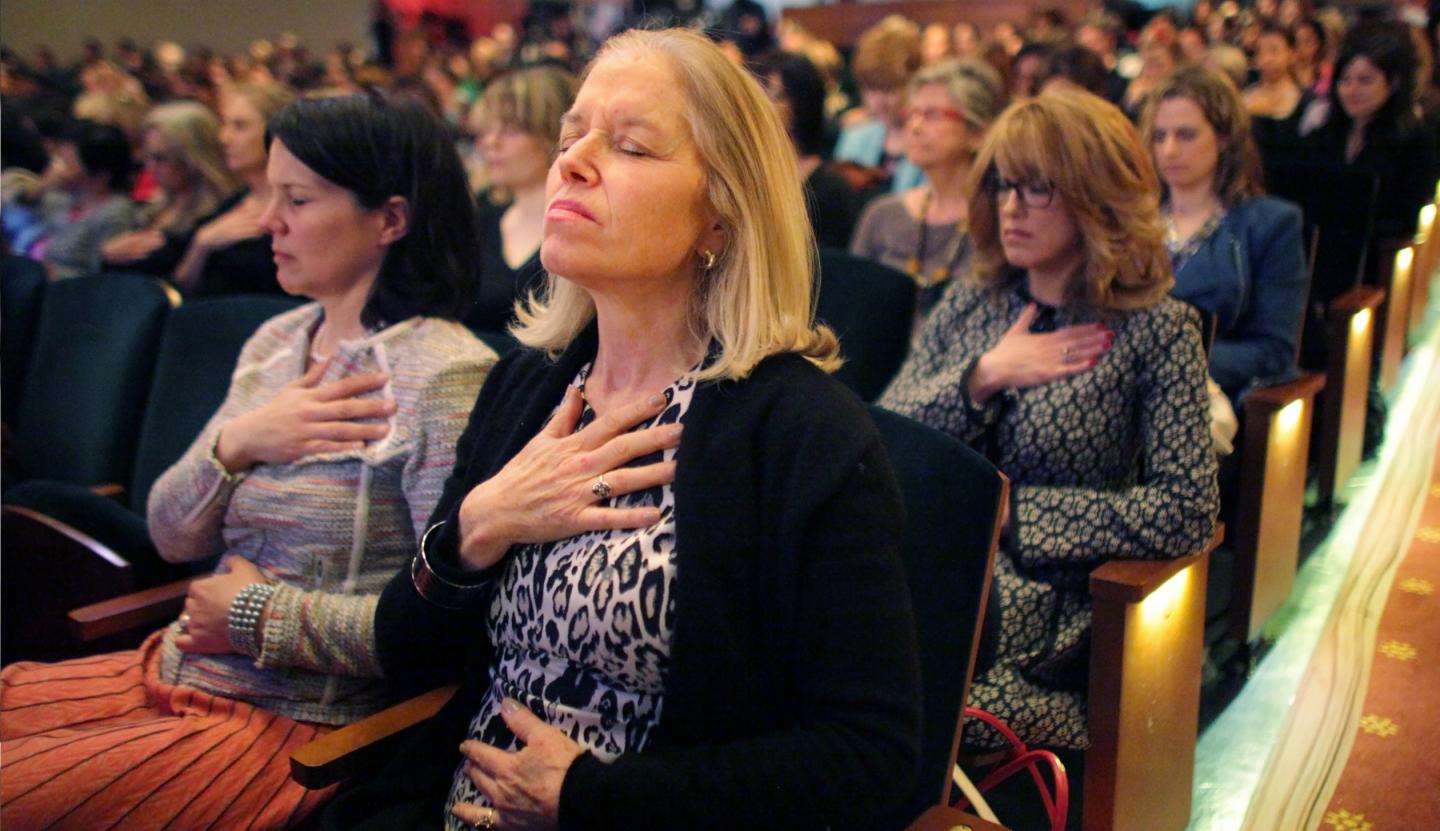 Audience members perform relaxation exercises under the guidance of Agapi Stassinopoulos, hostess Arianna Huffington's sister, during the THRIVE self-actualization seminar at the City Center in Manhattan, NY, 2014.