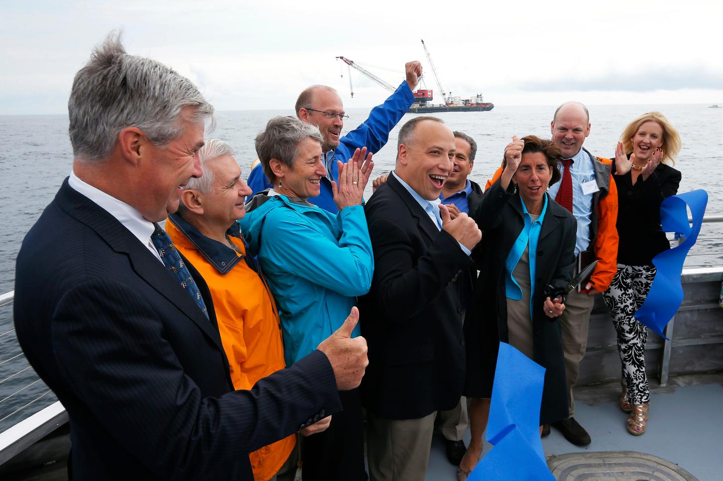 Elected officials and Deepwater Wind executives cheer during a ceremony to mark the installation of the first support jacket for a wind farm in the waters of the Atlantic Ocean off Block Island