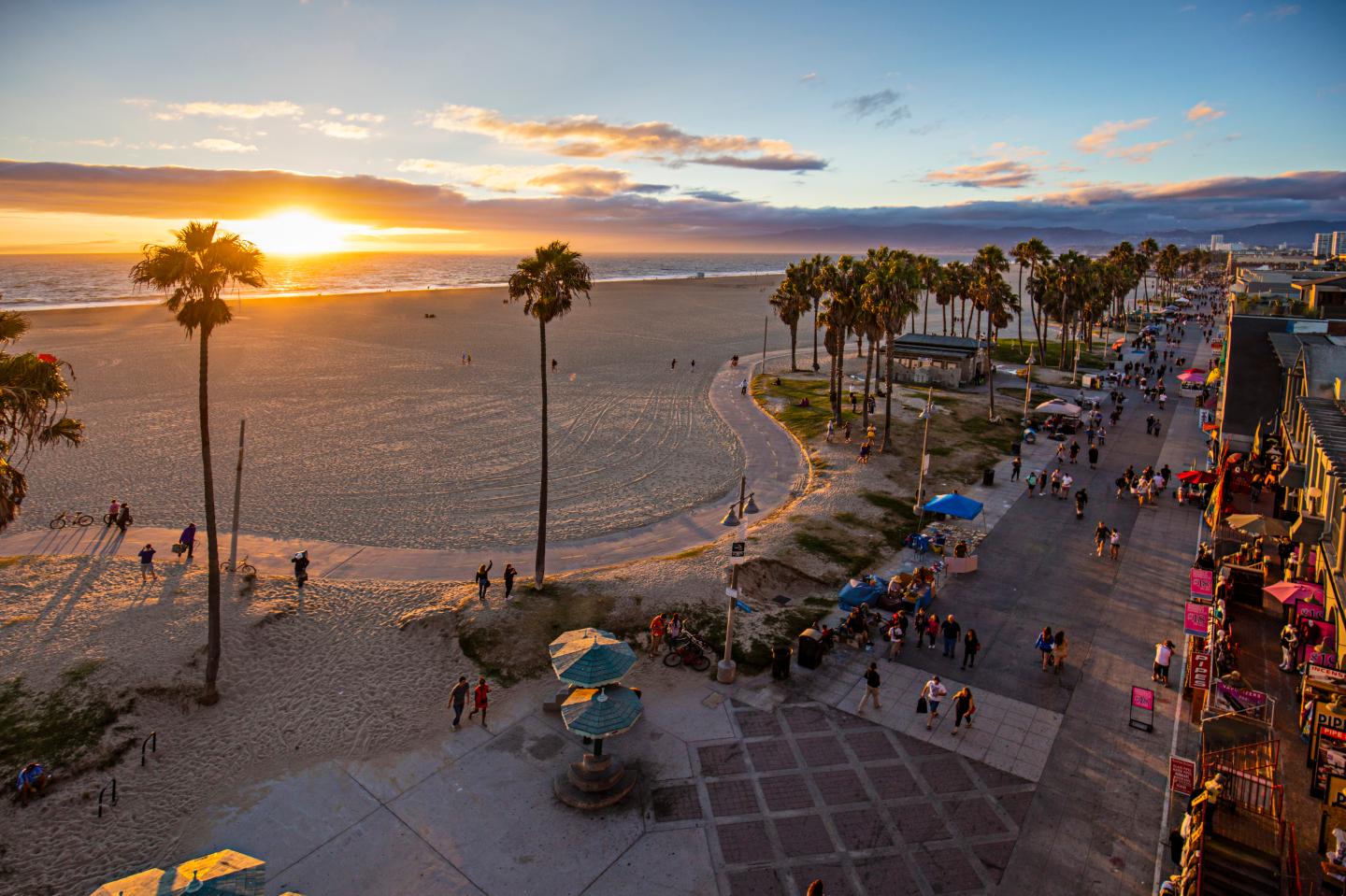 Tourists walking on footpath by beach during sunset