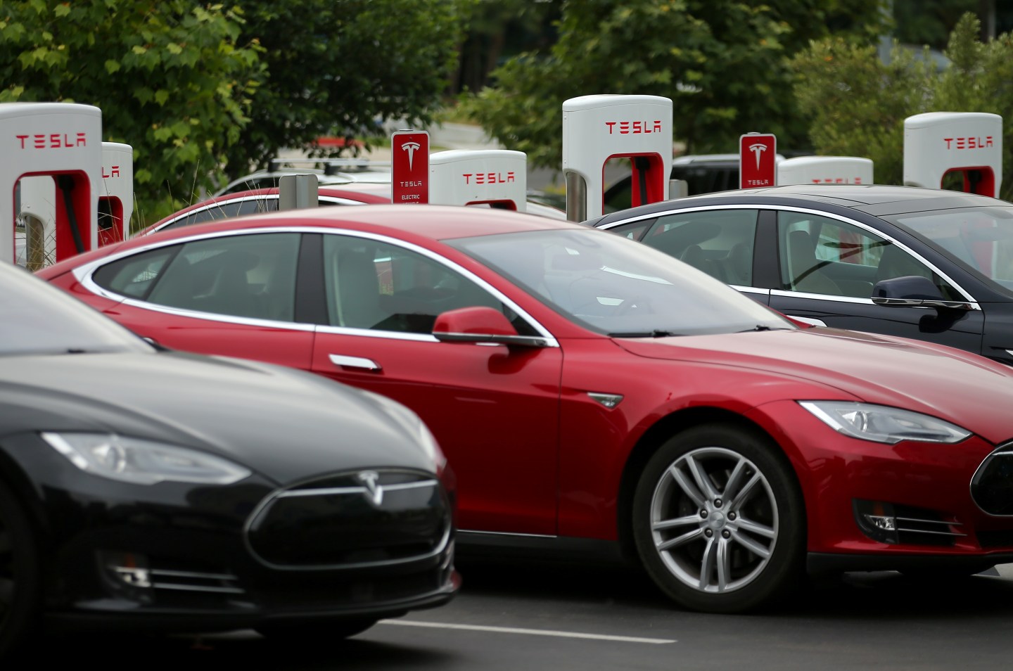 Tesla vehicles charge at a Tesla Supercharger station on the Qualcomm campus in San Diego