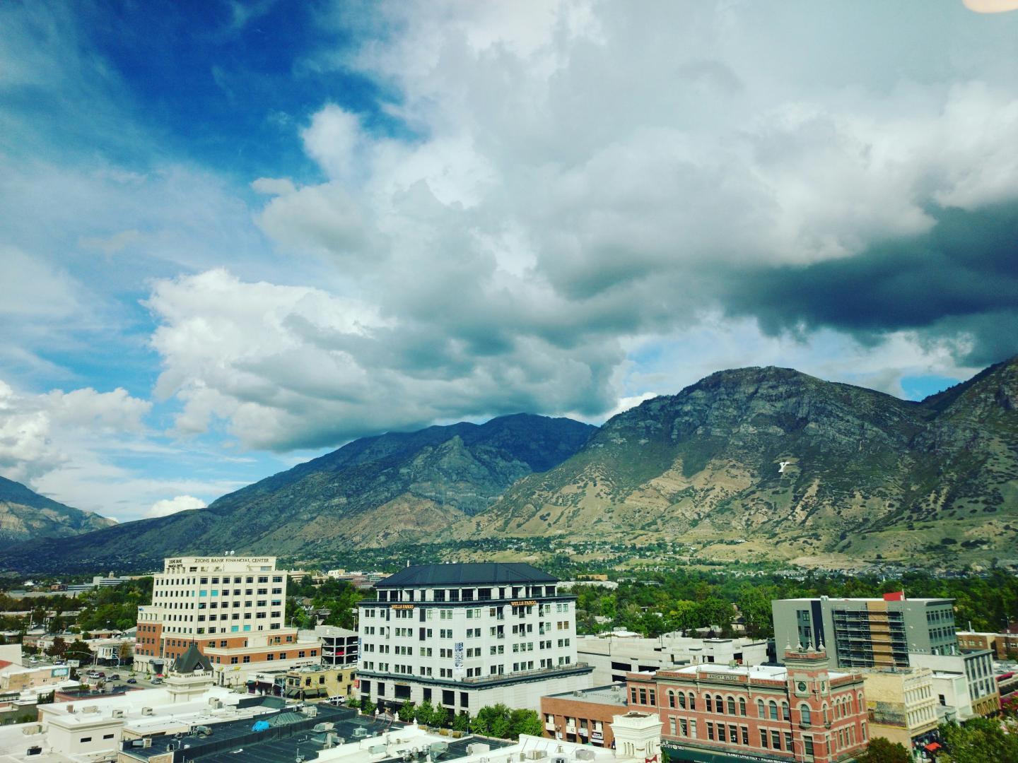 High Angle View Of Residential District By Mountains Against Cloudy Sky