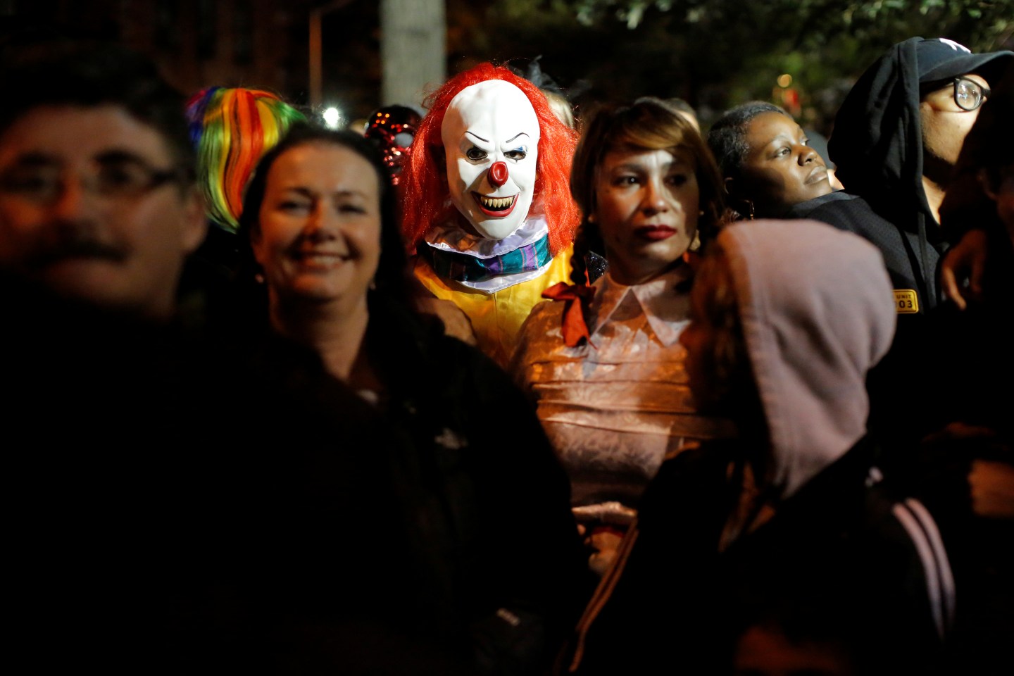 A person dressed in a clown costume stands amongst attendees during the Greenwich Village Halloween Parade in Manhattan, New York, U.S.