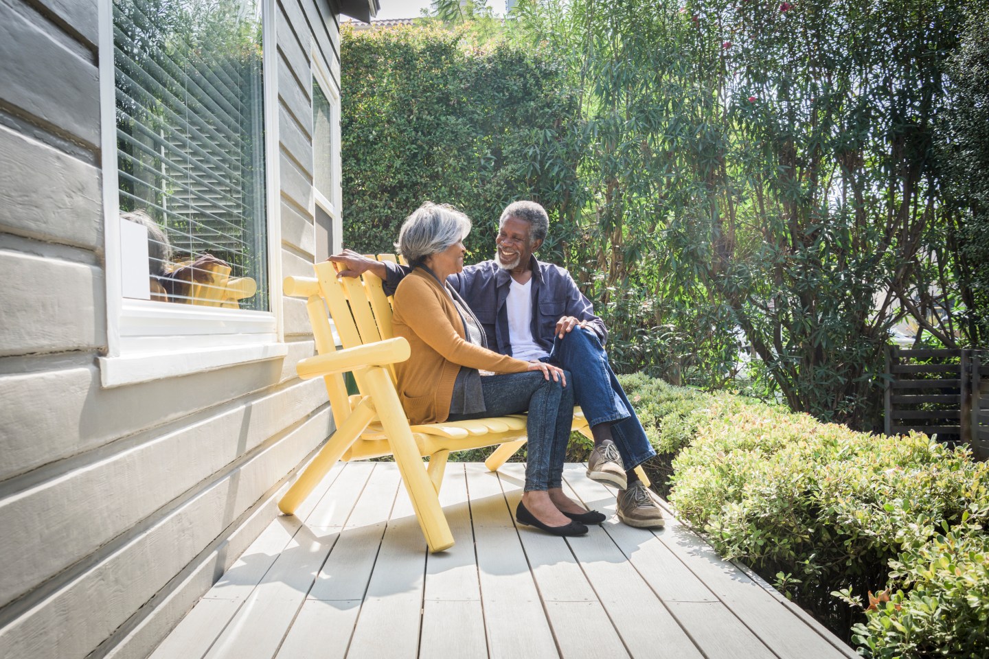 An older African American couple sitting on the porch of their house