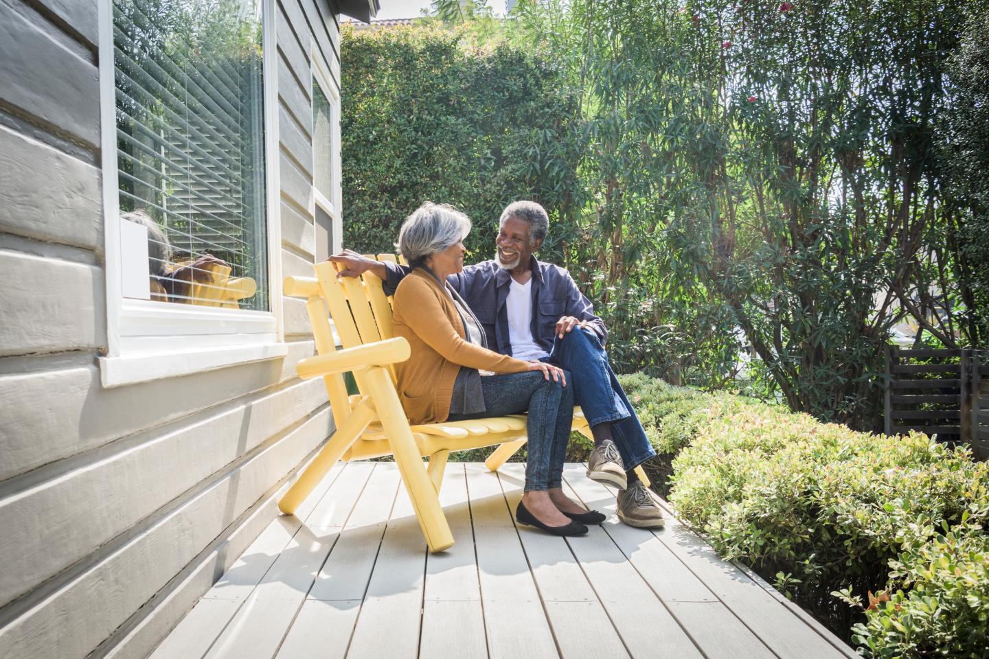 An older African American couple sitting on the porch of their house