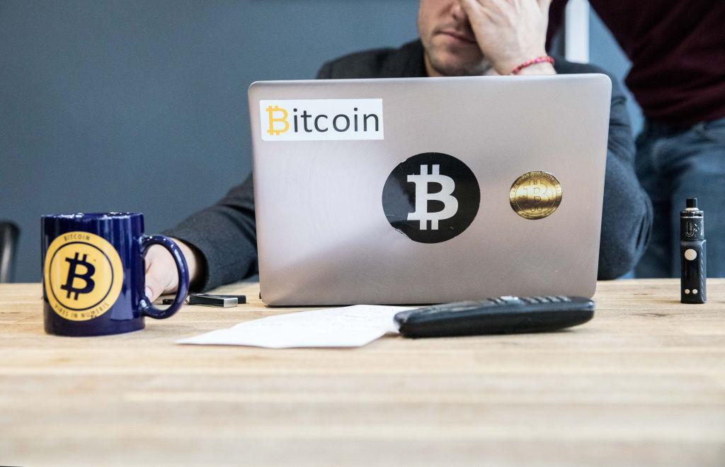 A Bitcoin trader with a Bitcoin-branded laptop and coffee mug.