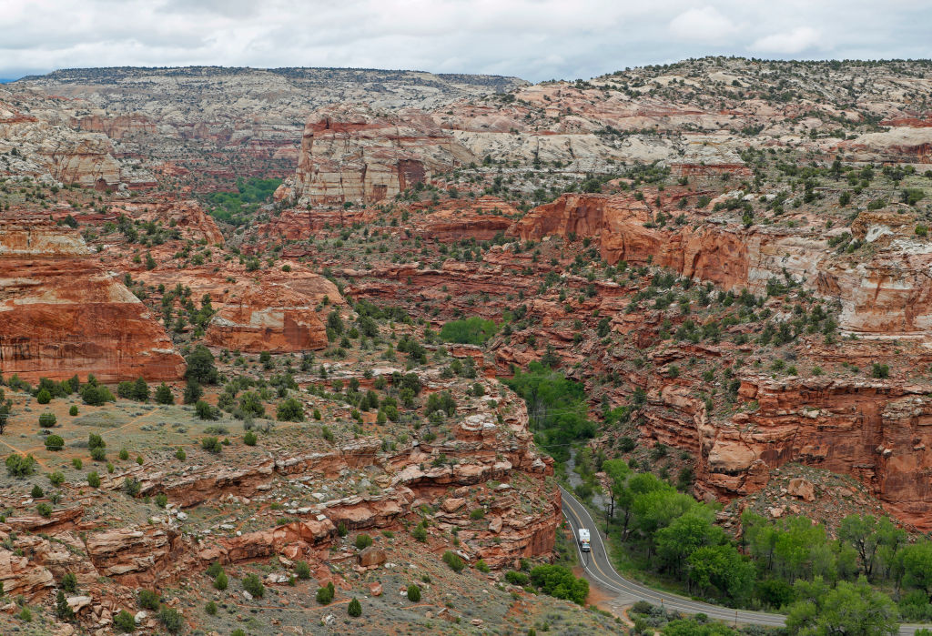 The dramatic orange and white plateaus of Grand Staircase-Escalante National Monument appear on either side of highway where RV drives