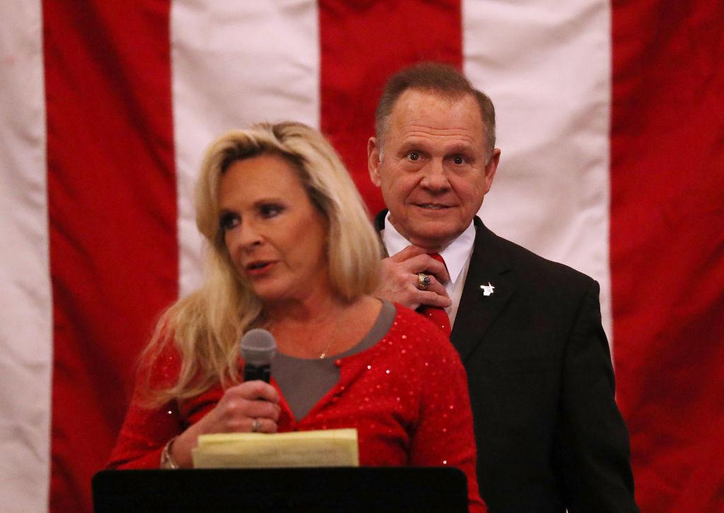 Roy Moore and wife Kayla appear on stage at campaign rally with American flag backdrop