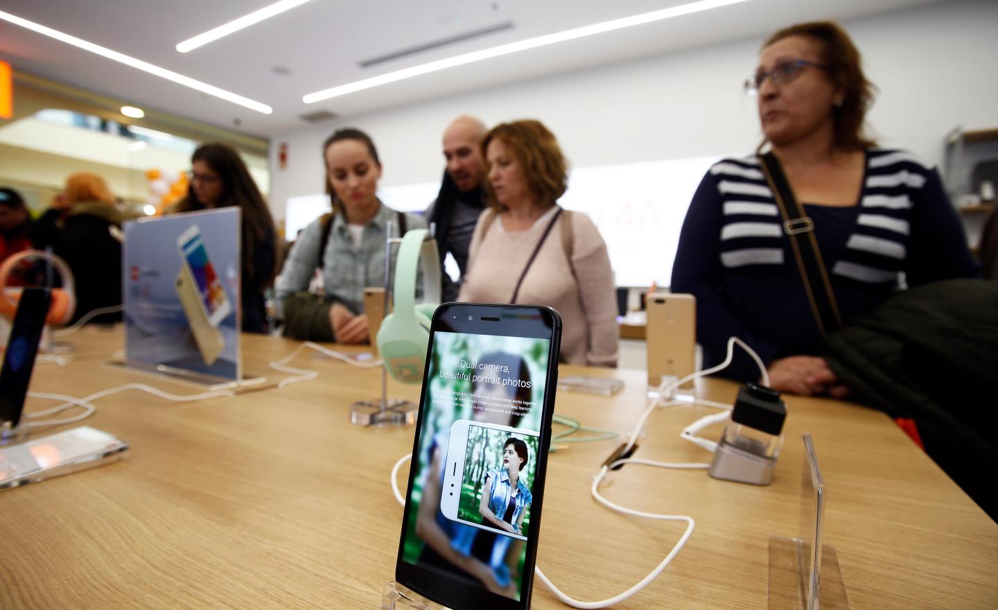 Customers stand at a table behind a smartphone display at Xiaomi's first store in Spain.