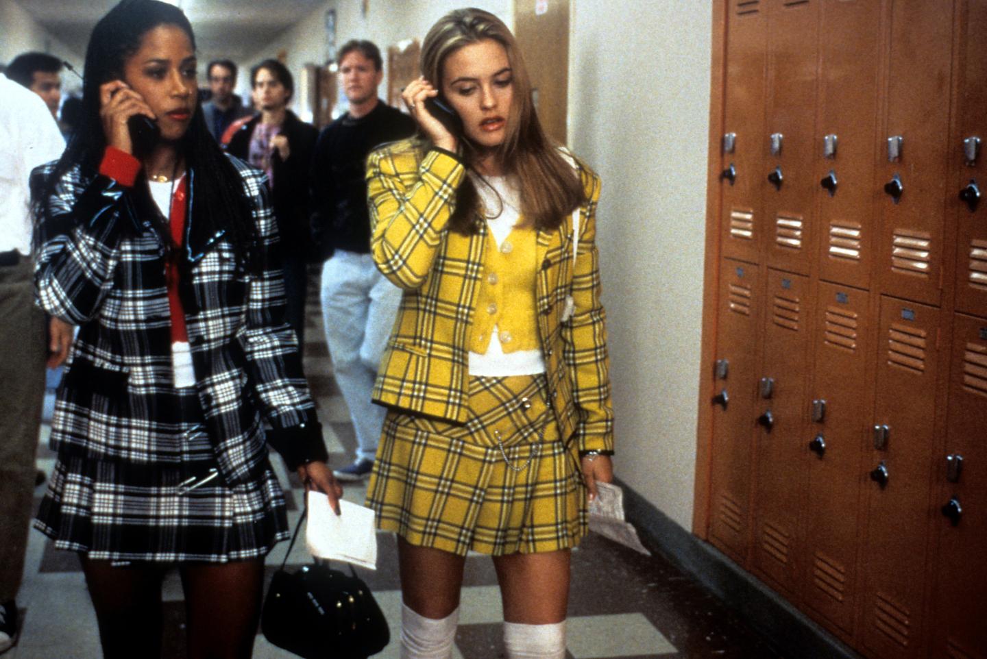 Stacey Dash And Alicia Silverstone talk on cellphones in a school hallway in a scene in the 'Clueless' movie