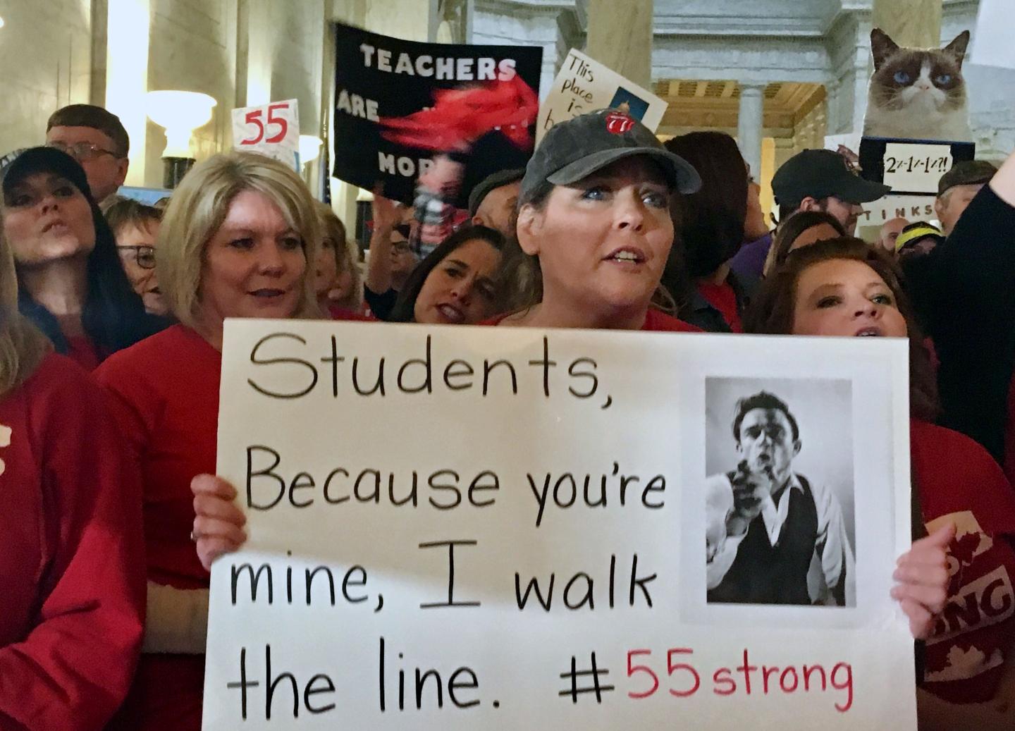 Female teacher hold sign protesting educator pay in West Virginia amid four-day teacher strike.