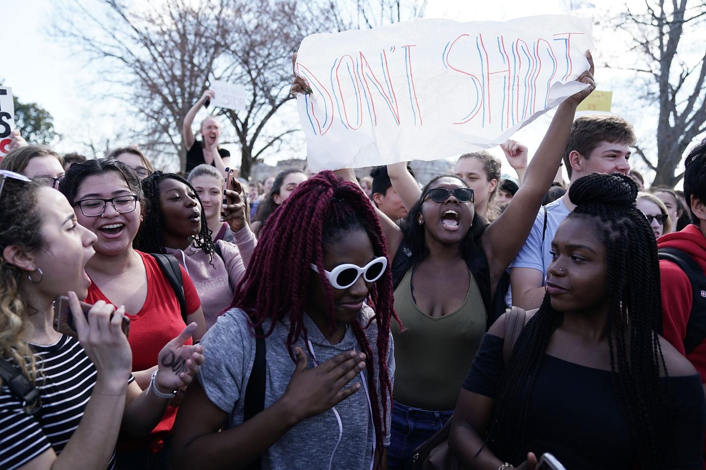 a group of students with one holding a "don't shoot" sign in the air