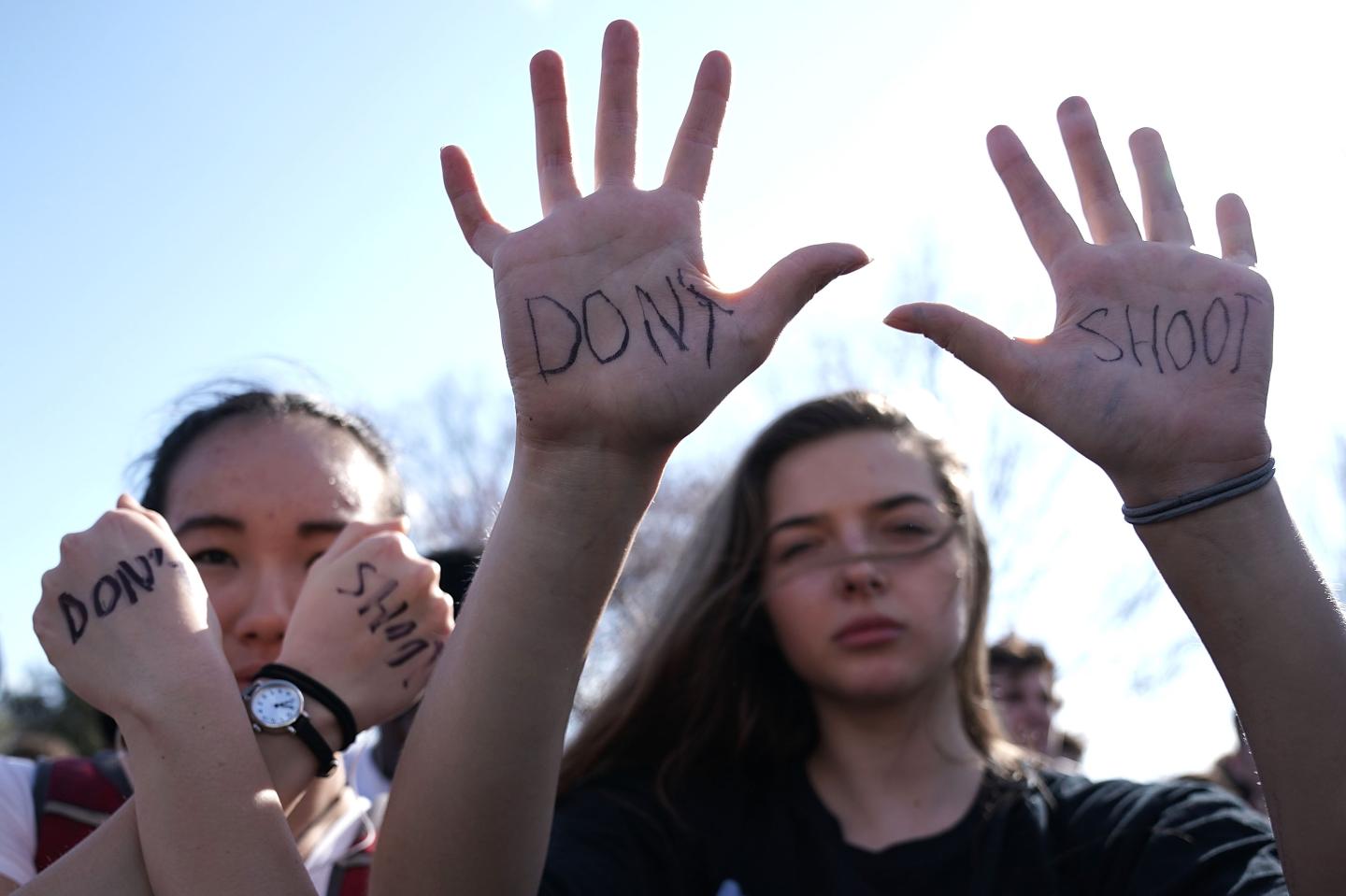 Two female students hold up their hands, where "don't shoot" has been scrawled