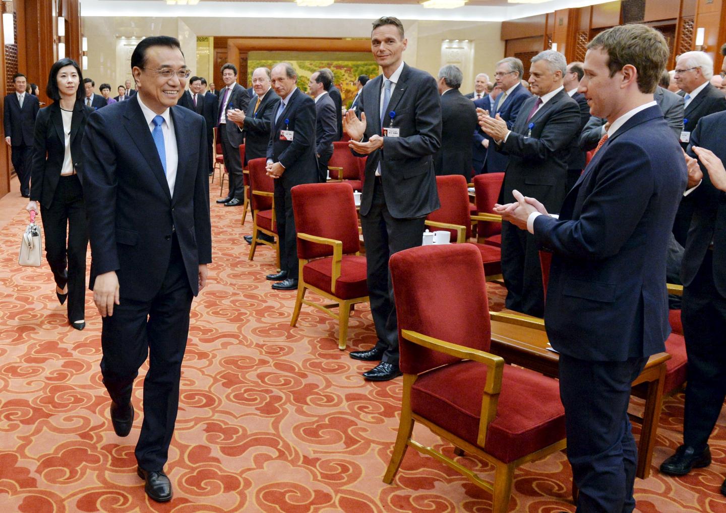 Facebook's CEO Mark Zuckerberg and the overseas representatives of China Development Forum applaud for the arrival of Chinese Premier Li Keqiang at a meeting at Great Hall of the People in Beijing