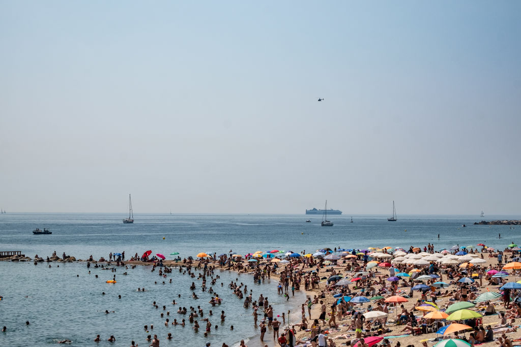 A crowd of people is seen on one of the beaches during a