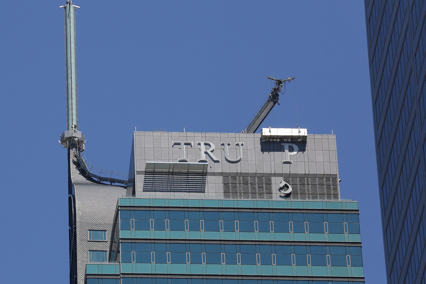 Workers remove letters from the "TRUMP" sign on top of the Trump International Hotel and Tower in Toronto