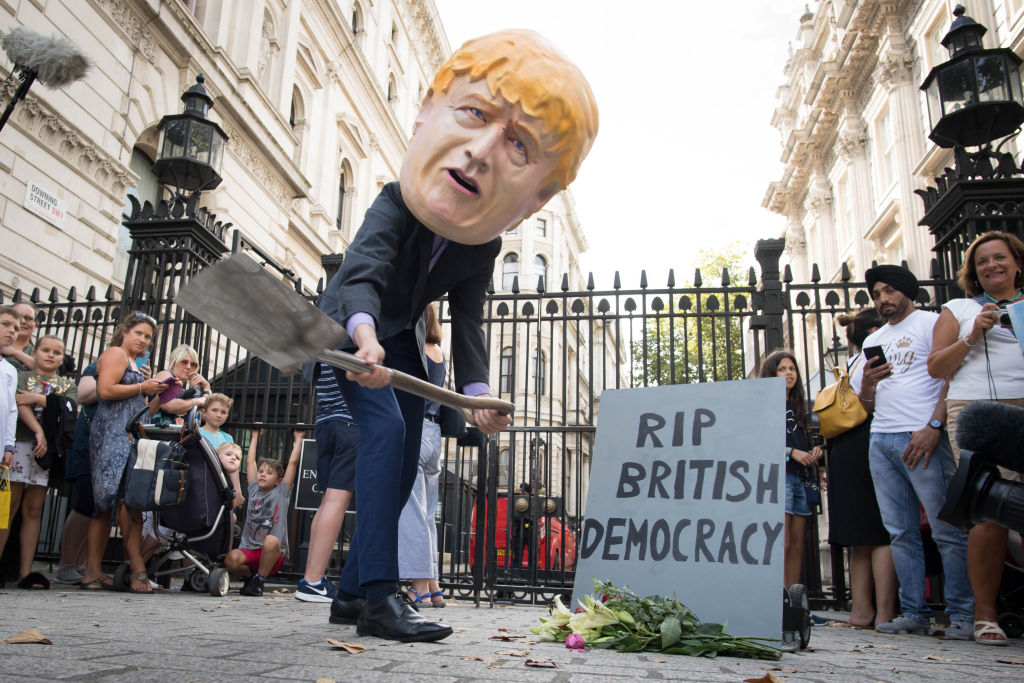A person wearing a Boris Johnson 'head' digs a grave at the foot of a tombstone during a protest organised by Avaaz and Best for Britain, outside Downing Street in London. (Photo by Stefan Rousseau/PA Images via Getty Images)