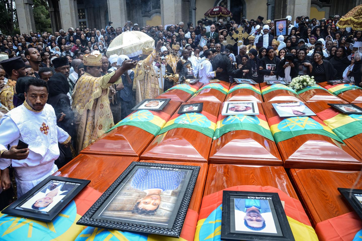 Priests hold a ceremony beside coffins of victims of the crashed accident of Ethiopian Airlines during the mass funeral at Holy Trinity Cathedral in Addis Ababa, Ethiopia, on March 17, 2019. - The crash of Flight ET 302 minutes into its flight to Nairobi on March 10 killed 157 people onboard and caused the worldwide grounding of the Boeing 737 MAX 8 aircraft model involved in the disaster. (Photo by Samuel HABTAB / AFP) (Photo credit should read SAMUEL HABTAB/AFP via Getty Images)