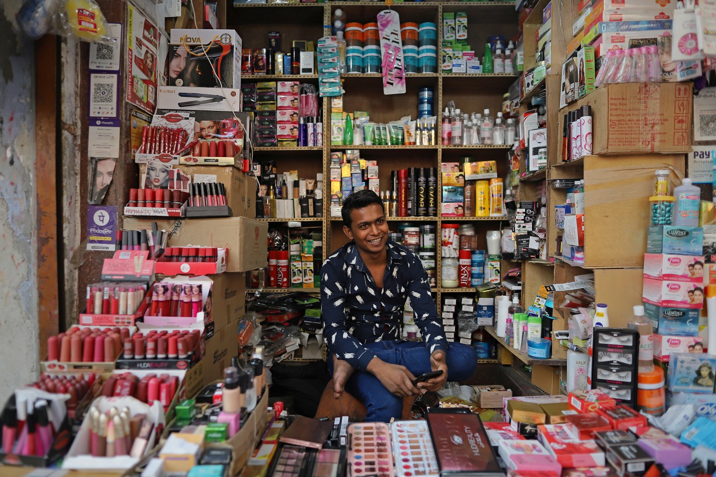 A vendor sits in a cosmetics store at Sadar Bazaar in New Delhi, India, on Wednesday, Nov. 20, 2019. In the heart of New Delhi's largest wholesale bazaar, merchants who normally compete with each other have united against a common enemy. The sit-in, which created more chaos than usual among the rickshaws, motorbikes and ox-carts plying the market road, was one of as many as 700 protests against Amazon.com Inc. and Walmart Inc. -- owner of local e-commerce leader Flipkart -- that organizers say took place at bazaars across India on a recent Wednesday. Photographer: Anindito Mukherjee/Bloomberg via Getty Images