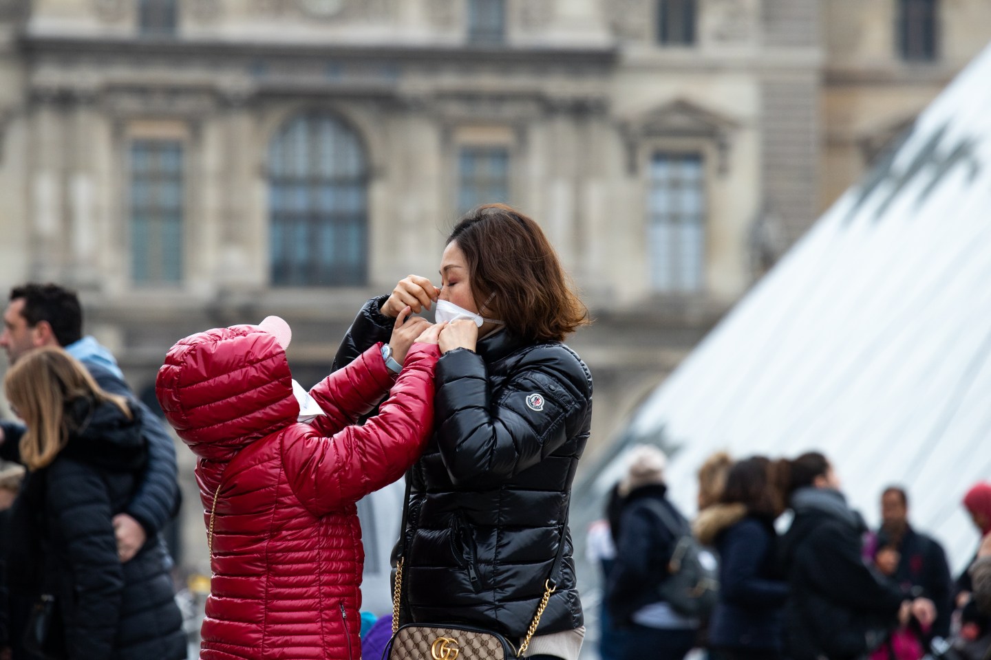A girl helping her mother wearing her safety mask near the Louvre Museum in Paris, France, on 26 January 2020. (Photo by Jerome Gilles/NurPhoto via Getty Images)