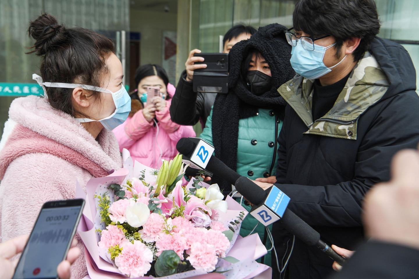 A woman (L), who recovered after being infected by a new coronavirus, speaks to the press as she walks out of a hospital in Bozhou, in China's eastern Anhui province on January 29, 2020. - A virus similar to the SARS pathogen has claimed 132 lives since emerging in a market in the central Chinese city of Wuhan, and spread around the world. (Photo by STR / AFP) / China OUT (Photo by STR/AFP via Getty Images)