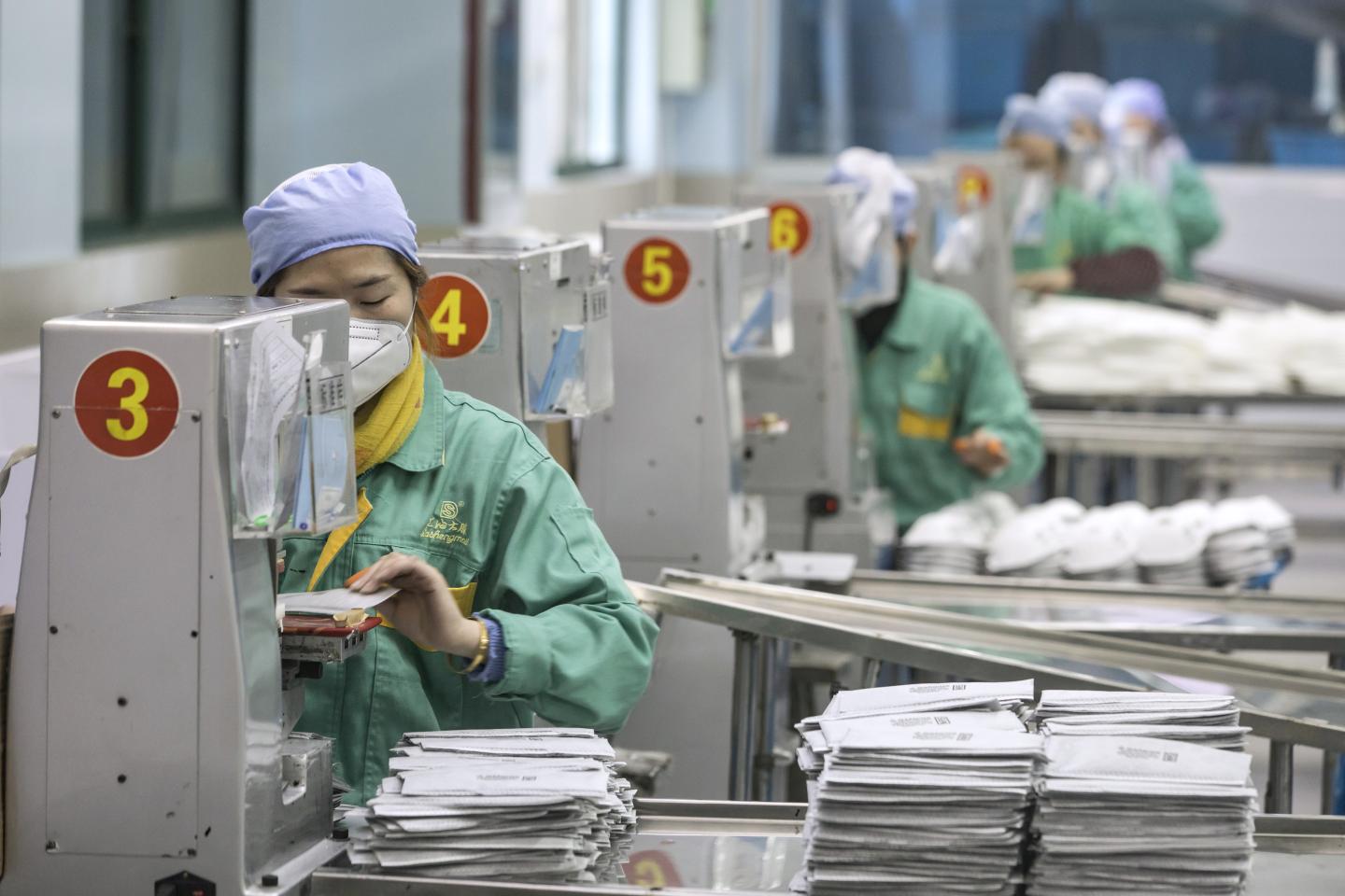 Employees work on the assembly line to make protective masks at a factory operated by Dasheng Health Products Manufacturing Co. in Shanghai, China, on Friday, Jan. 31, 2020. People across the globe are stockpiling facial masks to protect themselves from the new coronavirus, depleting online malls and store shelves from California to Beijing. Photographer: Qilai Shen/Bloomberg via Getty Images