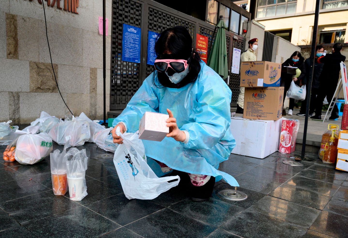 A woman wearing protective facemask and goggles collects delivered items that were ordered online outside her residential compound in Hangzhou, some 175 kilometres (110 miles) southwest of Shanghai on February 5, 2020. - The world has a "window of opportunity" to halt the spread of a deadly new virus, global health experts said, as the number of people infected in China jumped to 24,000 and millions more were ordered to stay indoors. (Photo by NOEL CELIS / AFP) (Photo by NOEL CELIS/AFP via Getty Images)