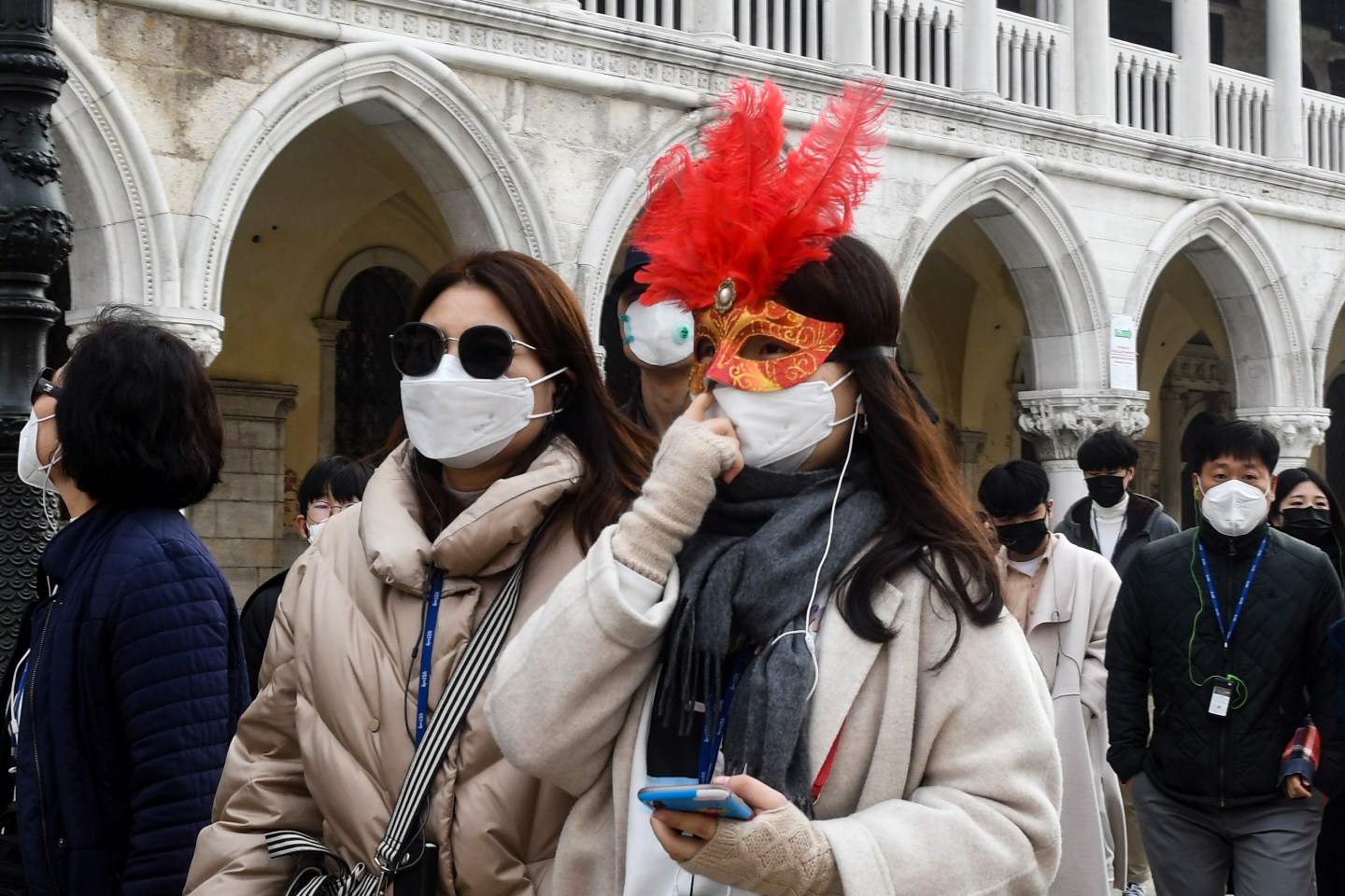Tourists wearing protective facemasks and a Carnival mask visit the Piazza San Marco, in Venice, on February 24, 2020 during the usual period of the Carnival festivities which the last two days have been cancelled due to an outbreak of the COVID-19 the novel coronavirus, in northern Italy. - Italy reported on February 24, 2020 its fourth death from the new coronavirus, an 84-year old man in the northern Lombardy region, as the number of people contracting the virus continued to mount. (Photo by ANDREA PATTARO / AFP) (Photo by ANDREA PATTARO/AFP via Getty Images)