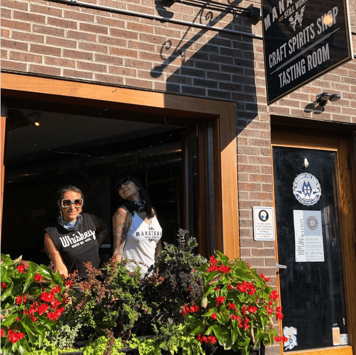 Operations manager Jennifer Sbatino leans out the front window of Stillworks' tasting room on Passyunk Avenue.