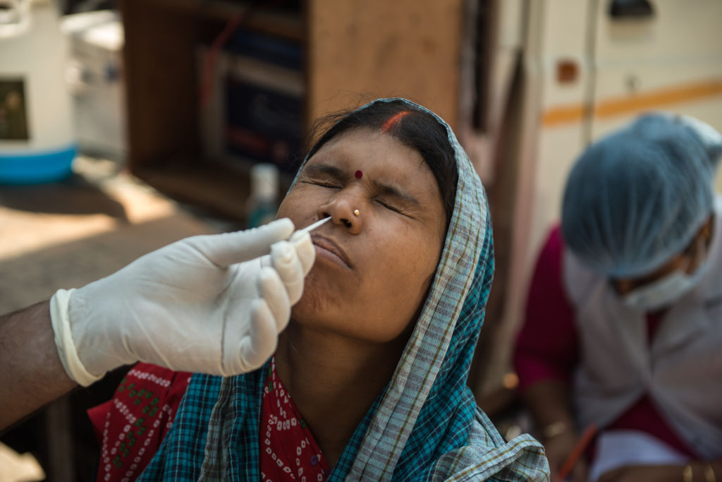 A woman reacts while a health worker takes a nasal swab