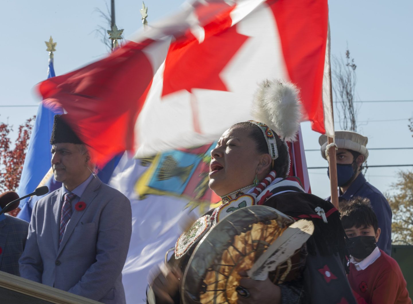 an indigenous woman in front of a Canadian flag