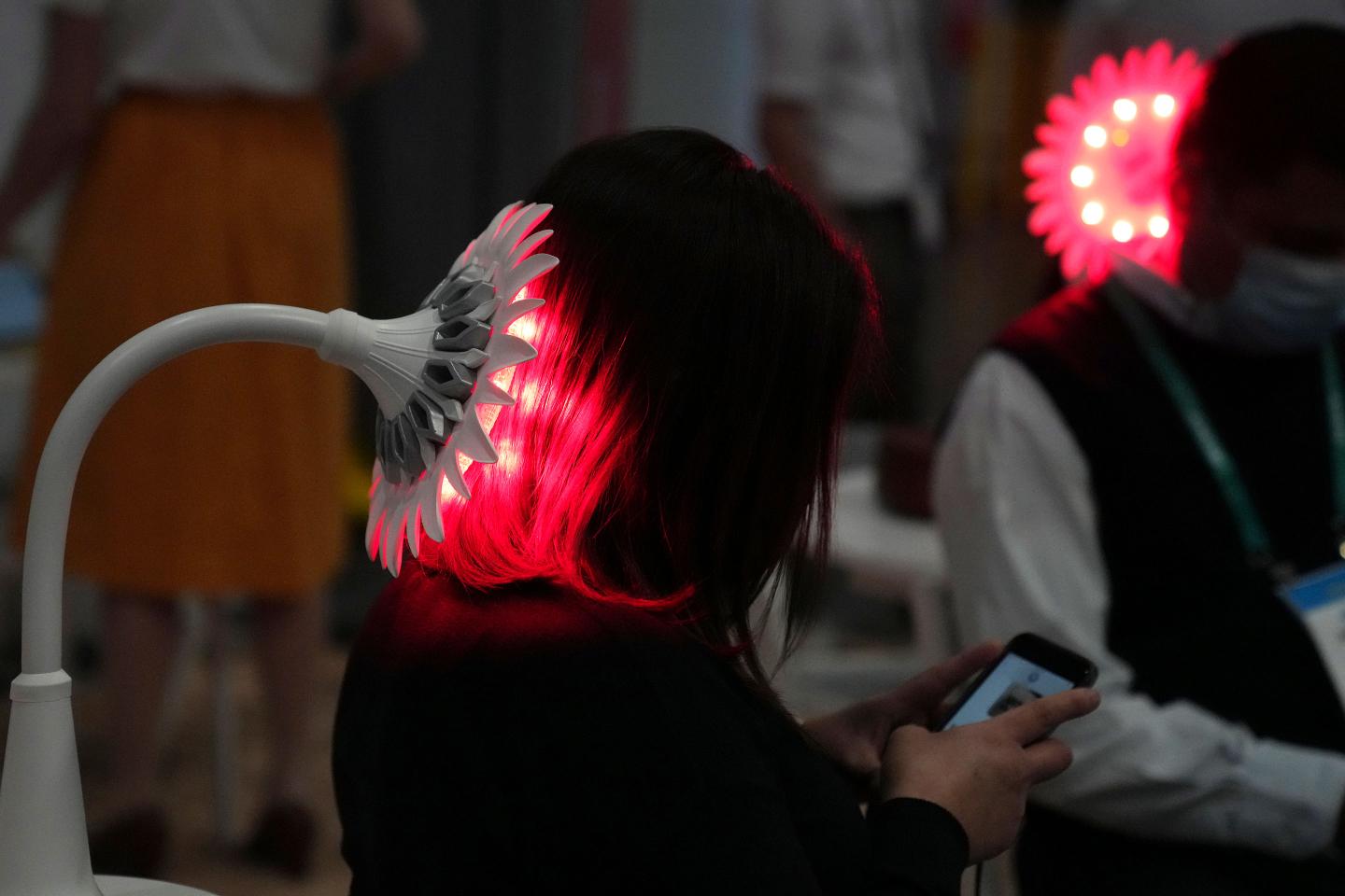 Attendees try out the Sunflower Light Therapy lamp at the JustLight booth.