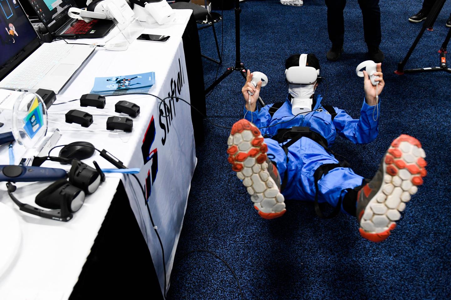 An attendee demonstrates the Shiftall Haritora X full-body tracking system and mutalk microphone for metaverse experiences while wearing an Oculus headset during CES Unveiled.