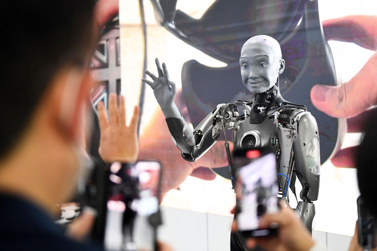 Attendees take pictures and interact with the Engineered Arts Ameca humanoid robot with artificial intelligence.