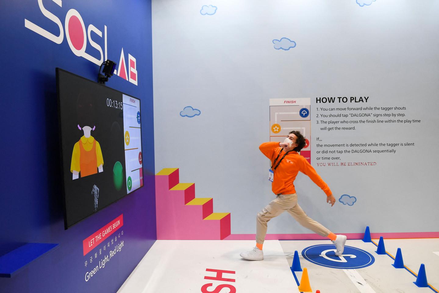 An attendee crosses the finish line while playing a LiDAR monitored game of Red Light Green Light at the South Korea-based SOS LAB company booth.