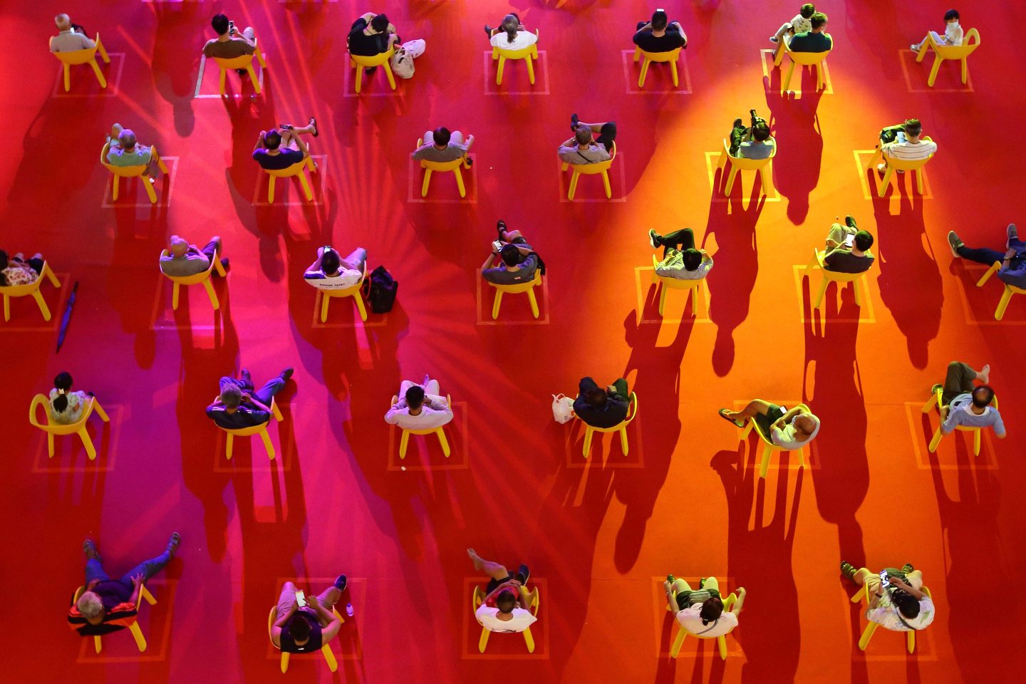 People sit on chairs marked to keep social distance