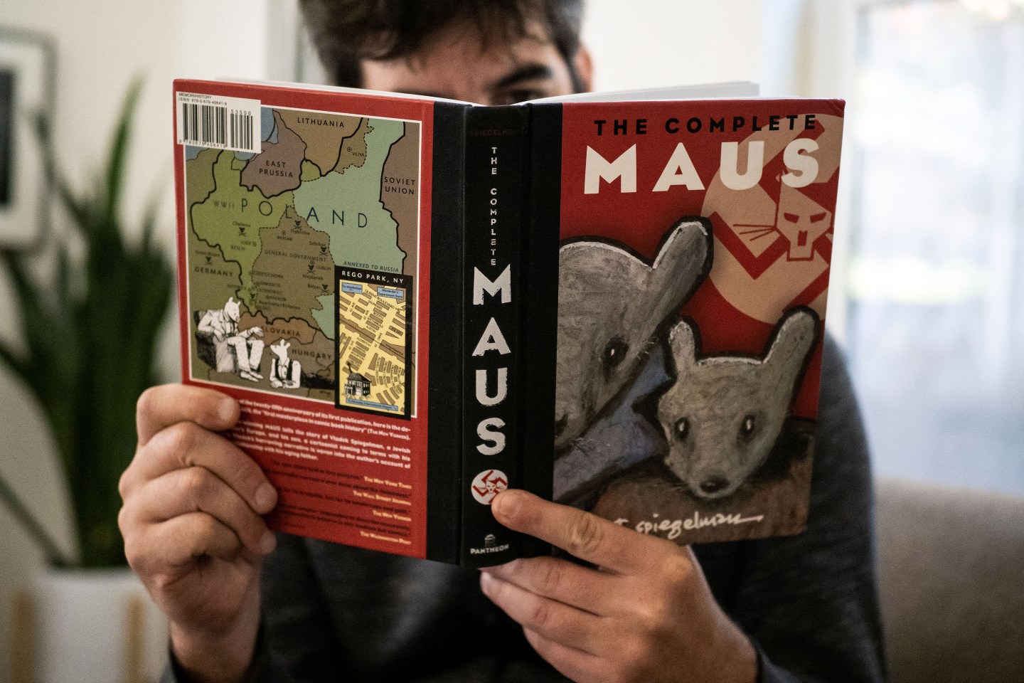A person holding the graphic novel "Maus" by Art Spiegelman.